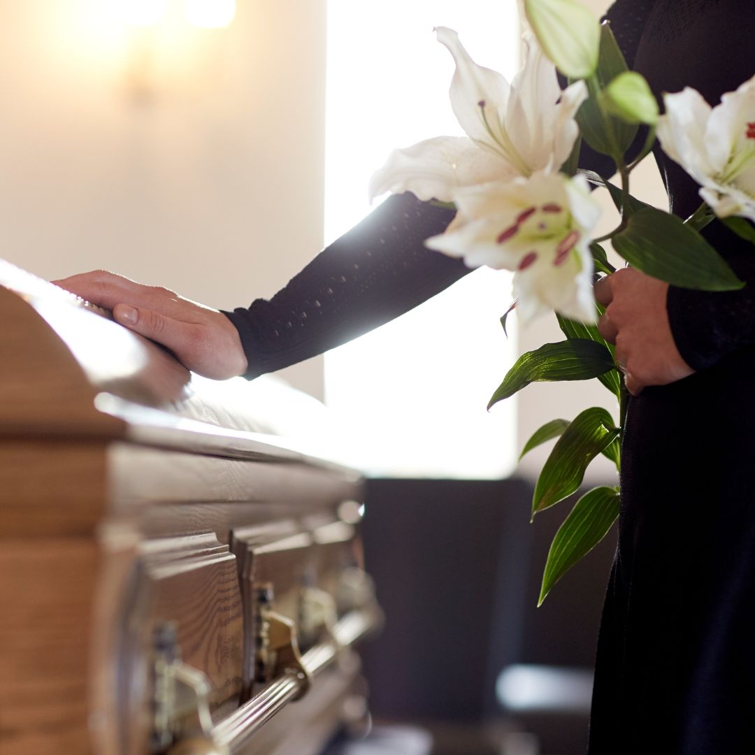 Someone laying lilies on a casket