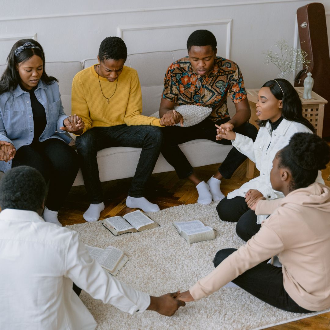 people at home holding hands in prayer