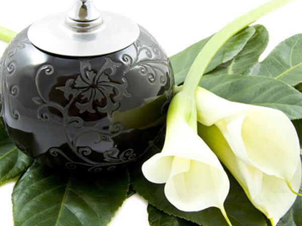 a black urn and a flower for cremation services