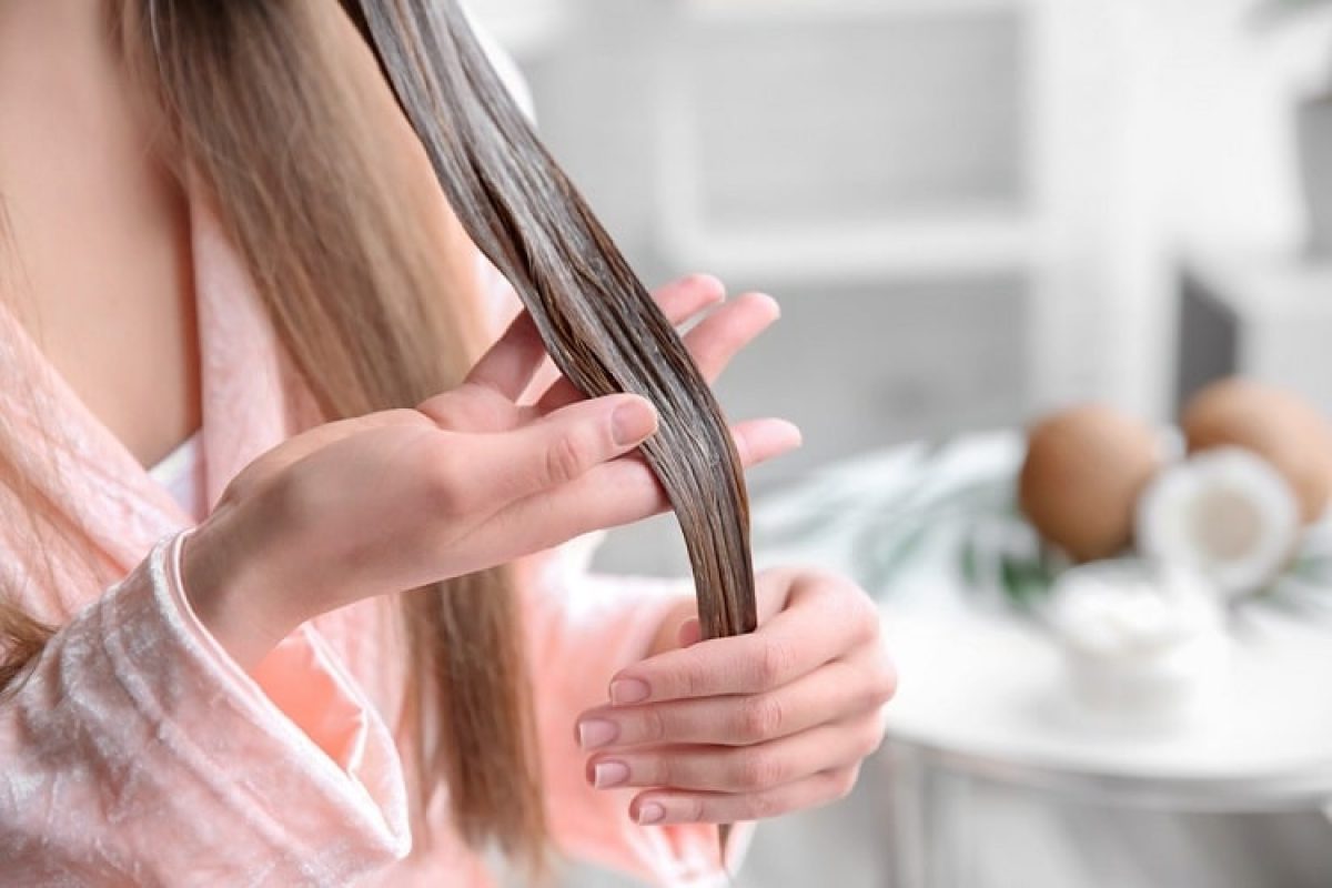 Mulher enluvando mecha de cabelo com óleo de coco ou máscara