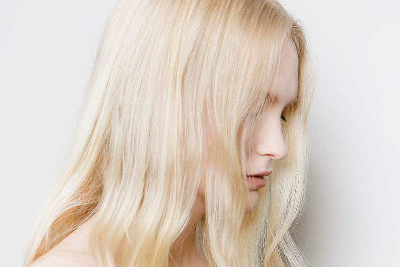 Menina de perfil com cabelo loiro claríssimo descolorido, sem danos