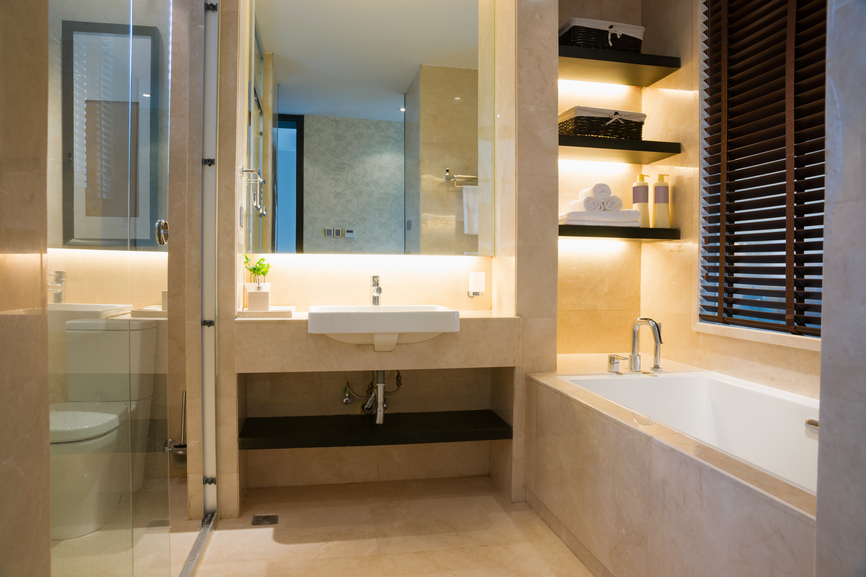 Small, but well laid out modern bathroom with single basin, tub and shower. One end of tub includes built-in shelving with back-lighting providing tub area ambient lighting