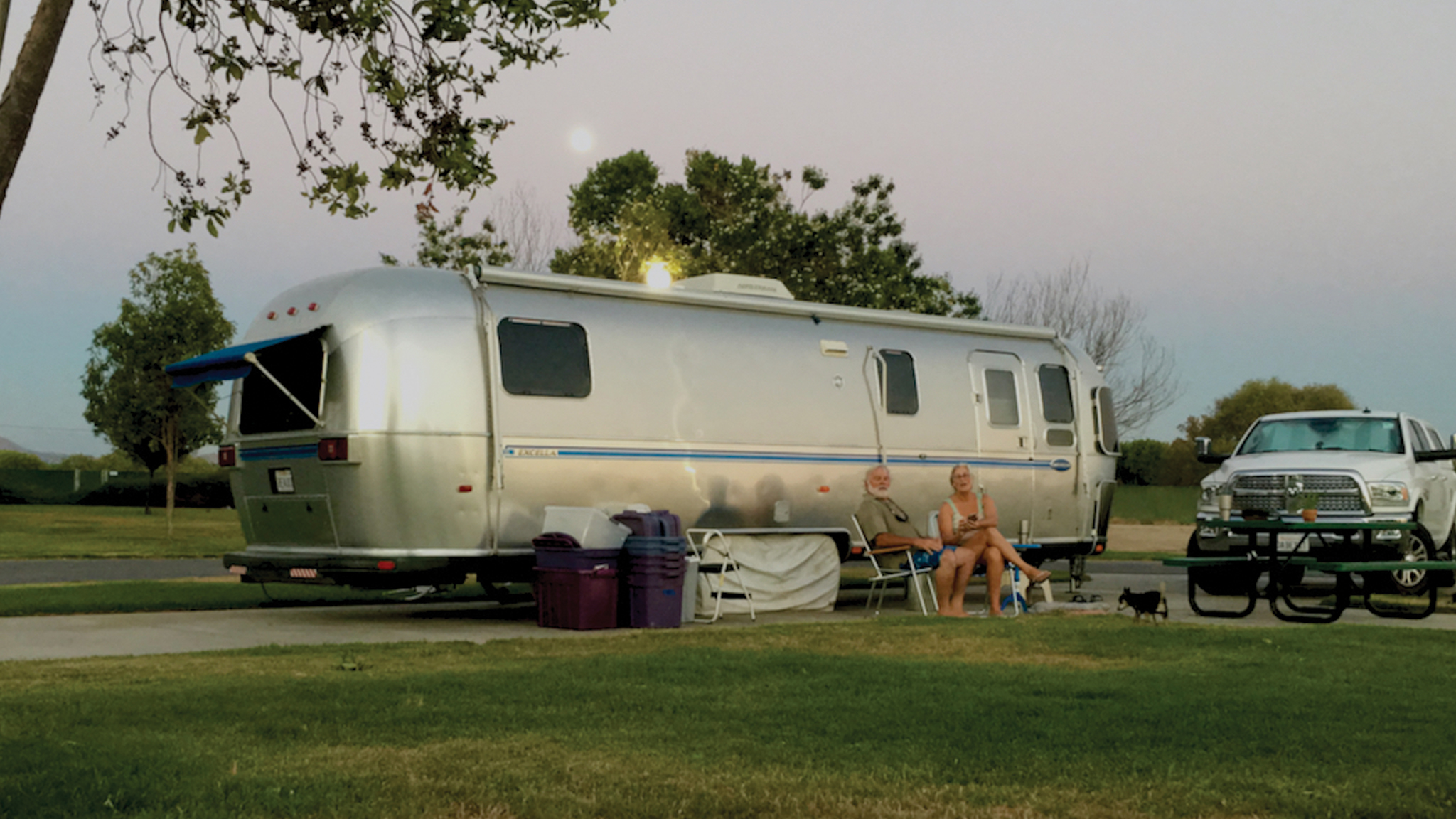 Jim and Carmen sitting outside of their Airstream Travel Trailer|An Airstream tire that is blown out on the side of the road|Jim fixing the tire on his Airstream Travel Trailer on the side of the road|Jim and Carmen when they were magicians|Jim using a sword box|Jim and Carmen looking out at a river|Living-in-Beauty-Champaigne|Living-in-Beauty-Champaigne|Living-in-Beauty-Blow-Out|Airstream travel trailer parked at campground|Jim and Carmen sitting in a hot spring|Living-in-Beauty-Back-Window|Jim and Carmen sitting at a River|Jim and Carmen sitting outside of their Airstream Travel Trailer