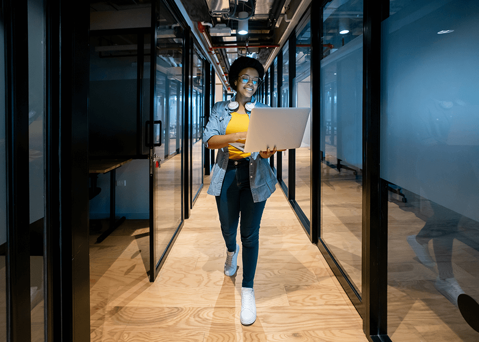 Woman IT manager walking office hall with laptop