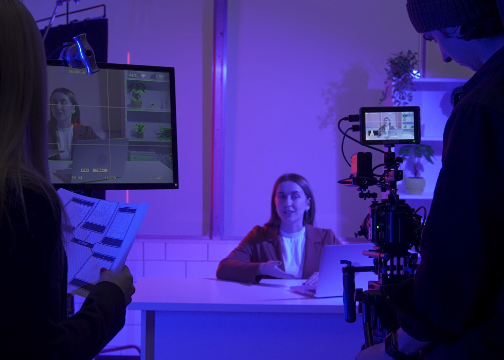 Crew with female producer recording female presenter in blue studio