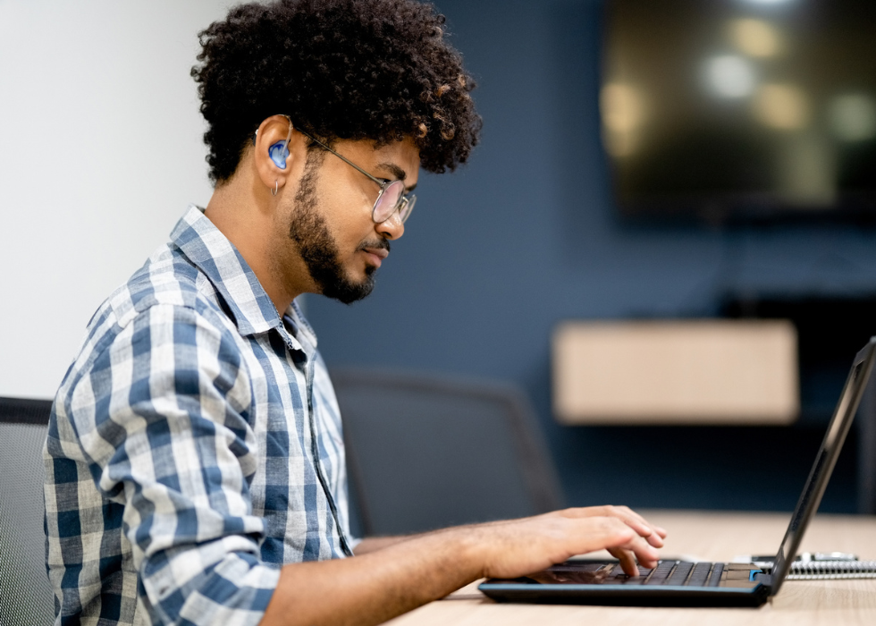 Man with hearing aid with laptop