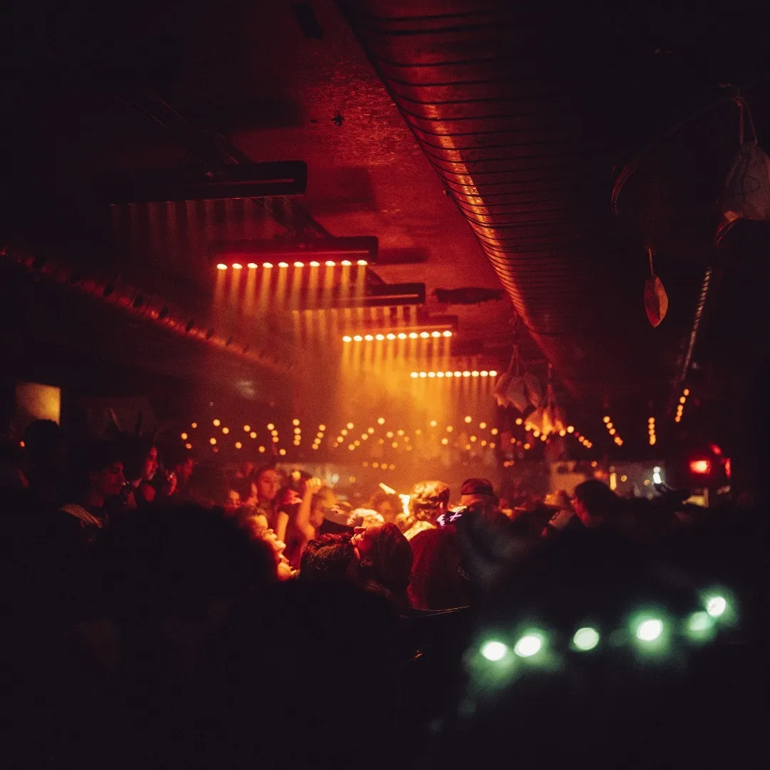 Vibrant nightclub scene at Le Rouge Bar Montreal, bustling with lively crowd under warm, glowing lights and dynamic ceiling decor.