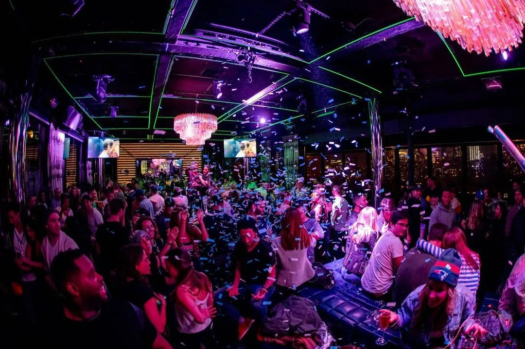 Vibrant nightclub scene at PHD Rooftop New York with a lively crowd, colorful lights, and a chic ambiance.