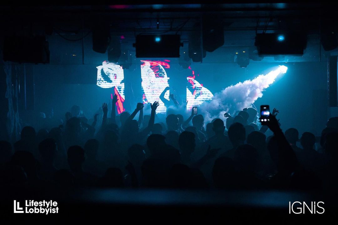 Crowded nightclub scene at Ignis Hong Kong with vibrant lights and a DJ in action, partygoers dancing and enjoying the night.