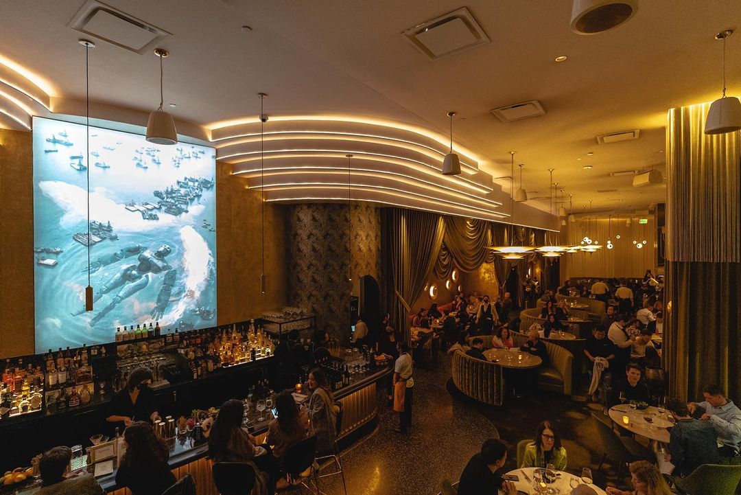 Interior of Animae San Diego Restaurant featuring a stylish bar, cozy seating, elegant lighting, and a large digital art display.