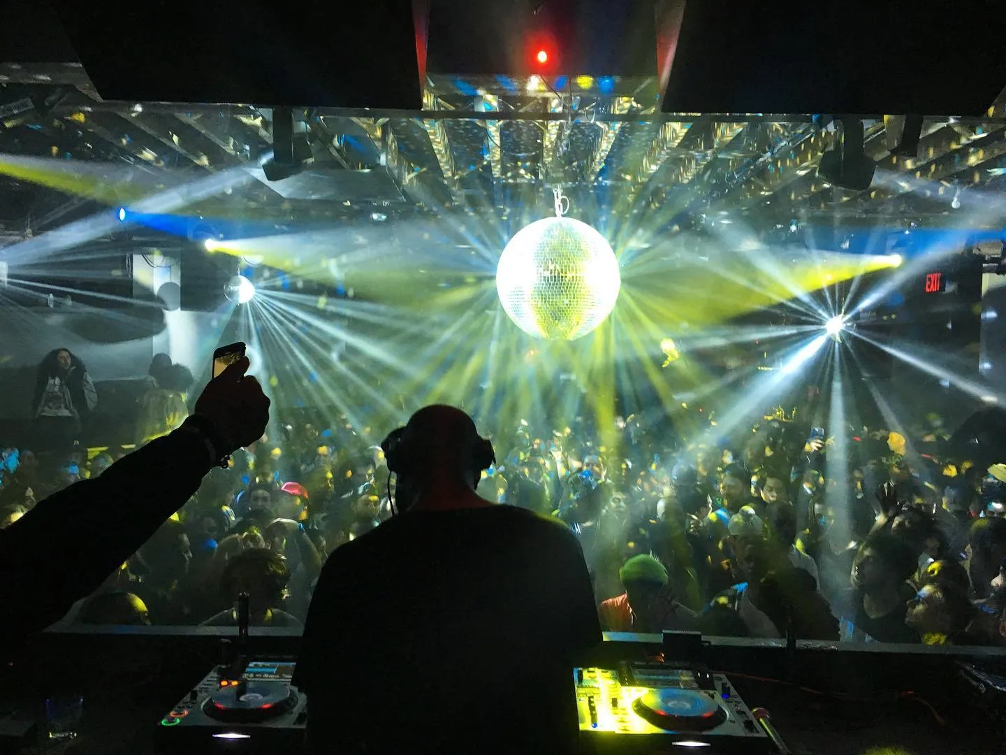 Vibrant nightclub scene at Schimanski New York, featuring a DJ at the decks, dazzling lights, and a lively crowd.