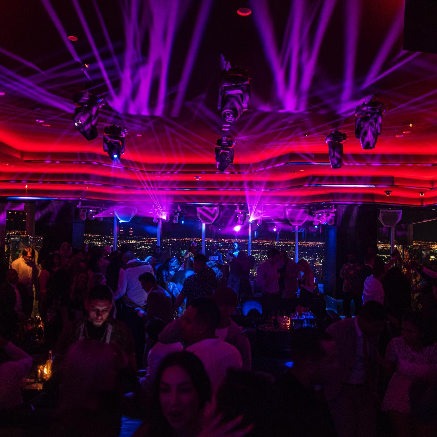 Vibrant Apex Social Club in Las Vegas with lively crowd, dazzling purple lights, and panoramic city views.