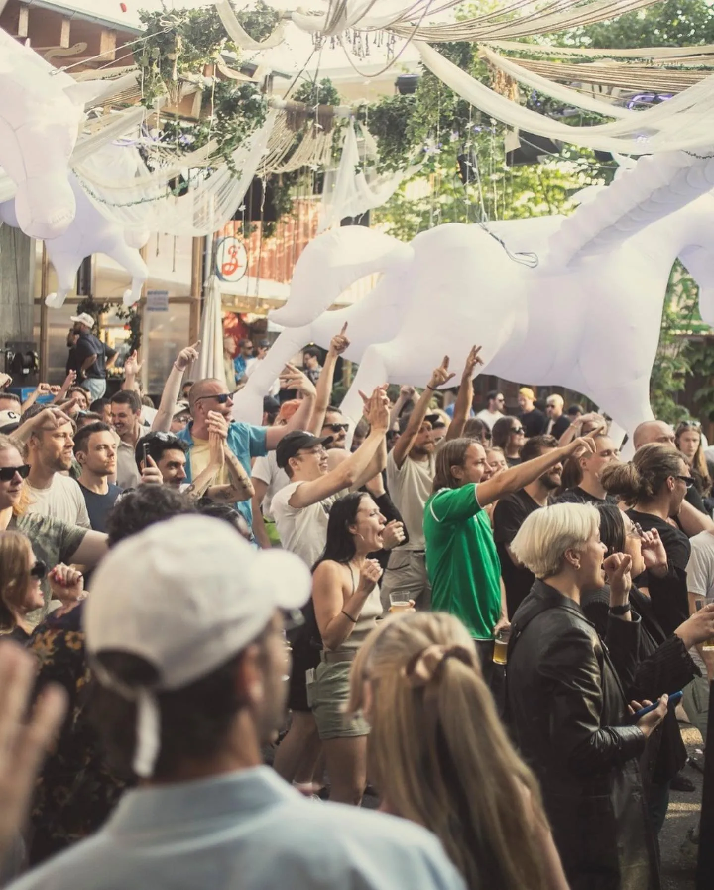 Alt caption: Lively outdoor party at Trädgården Nightclub, Stockholm, with a crowd dancing under hanging white decorations and inflatable art.