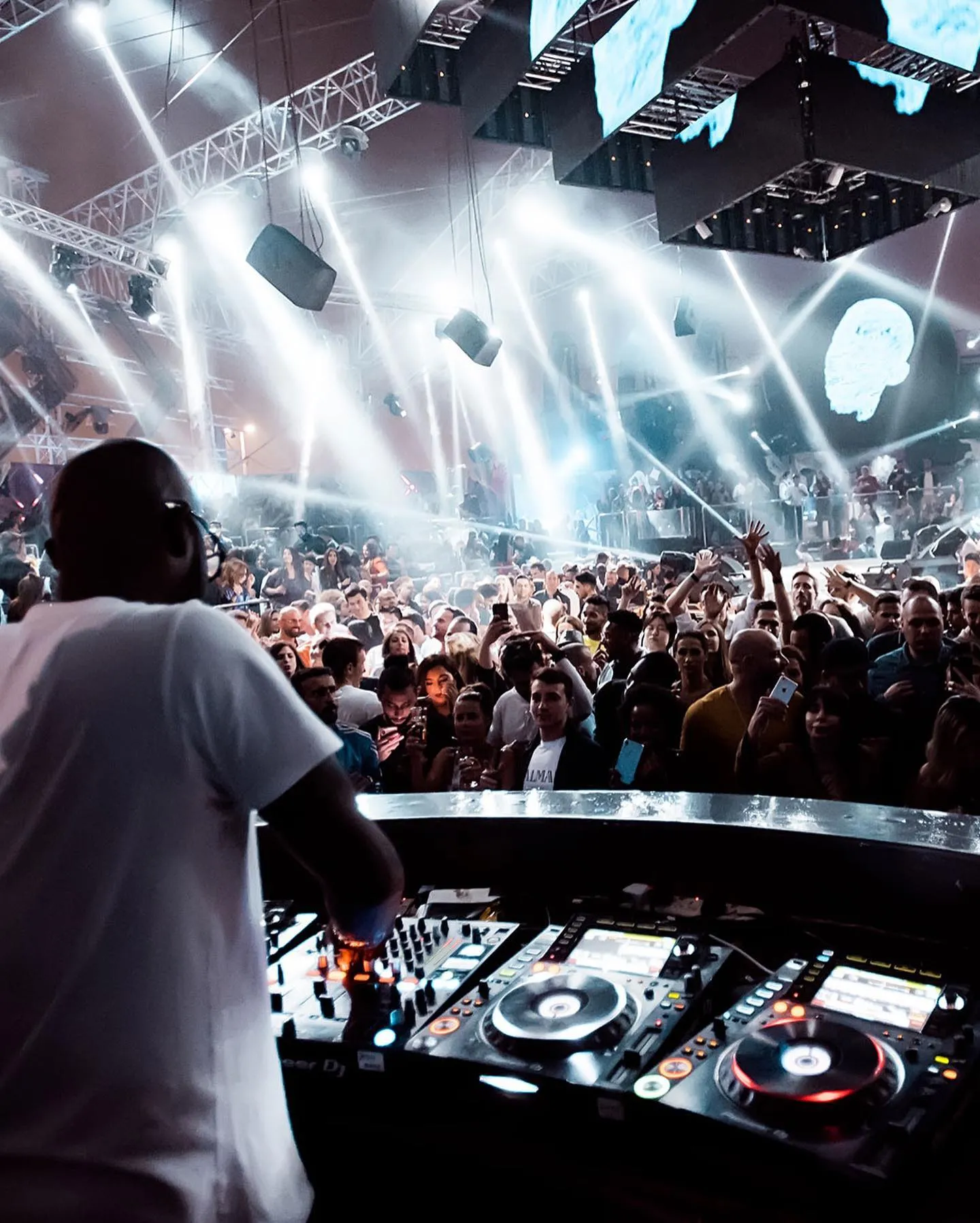 DJ performing at BASE Dubai nightclub with a crowd of people dancing under vibrant lights and dynamic visual effects.
