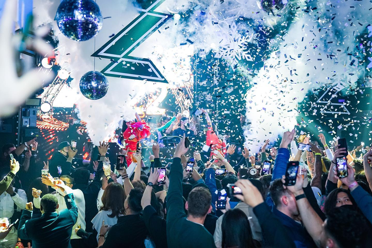 Vibrant nightclub scene at Zeus Tokyo with a crowd enjoying a live performance, dazzling lights, confetti blast, and multiple disco balls.