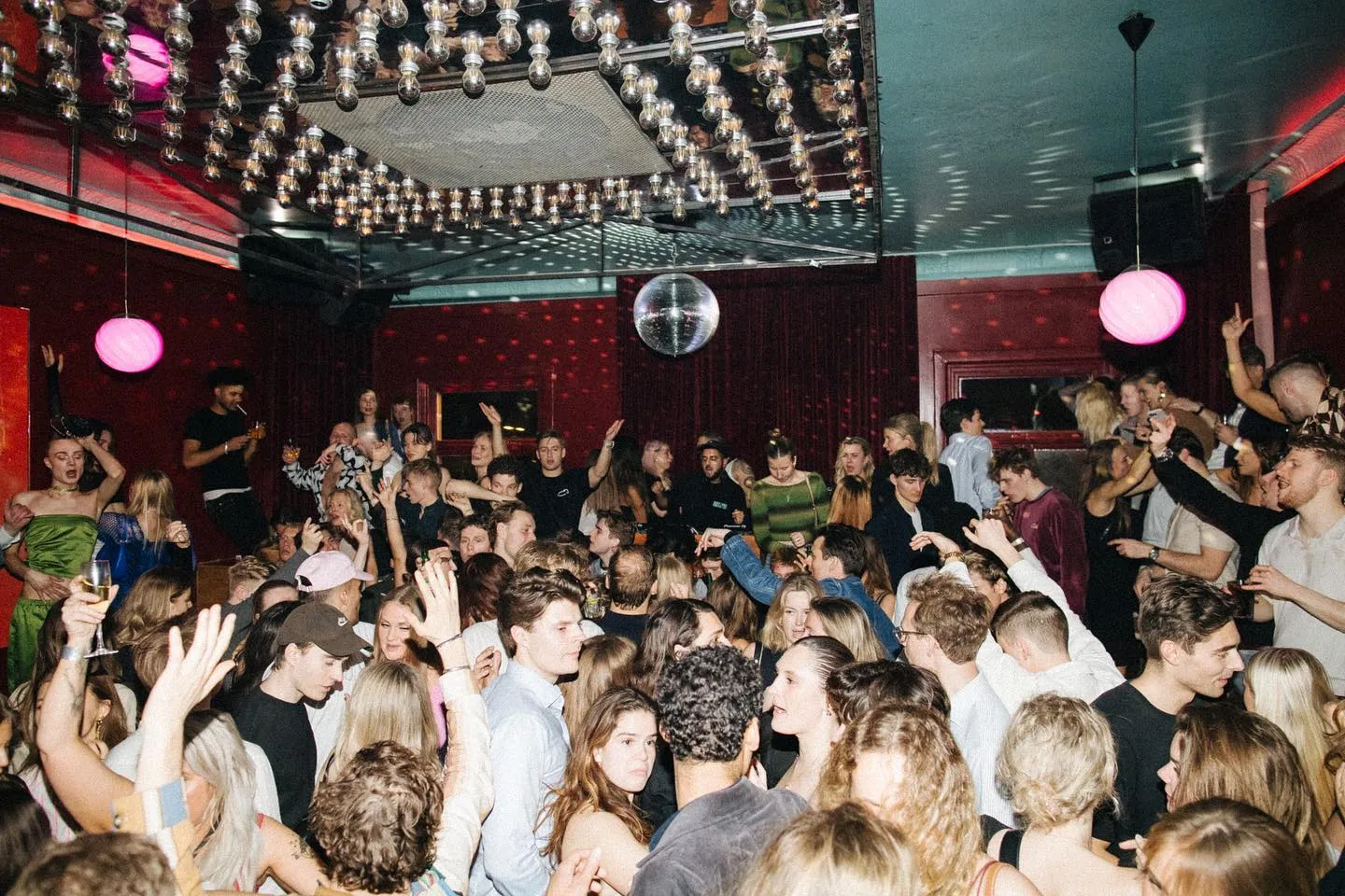 Vibrant nightclub scene with energetic crowd dancing under disco balls and colorful lighting at Sø Pavillionen in Copenhagen.