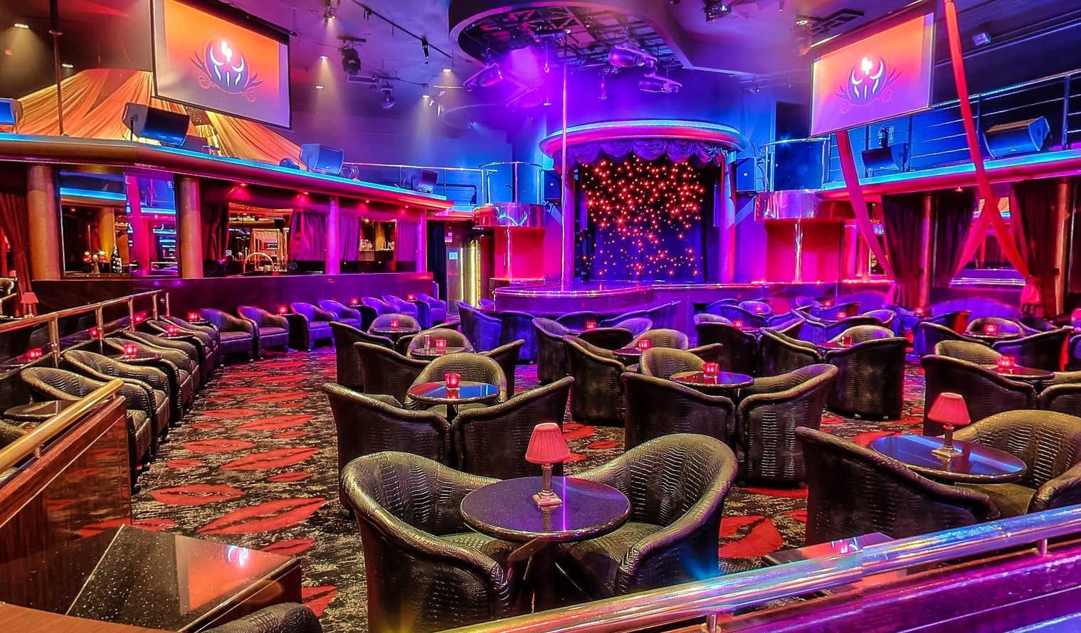 Vibrant nightclub interior with modern seating arrangements, colorful lighting, and an enticing stage set for an unforgettable night out.