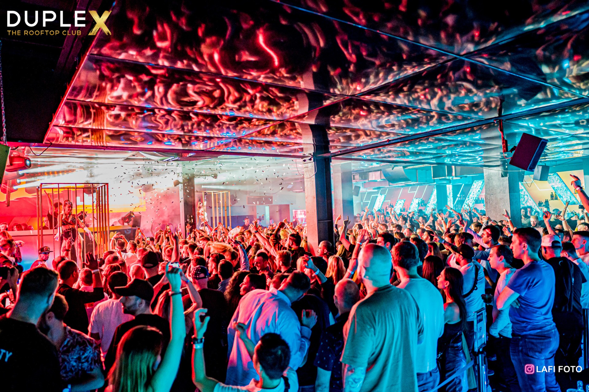 Vibrant rooftop party at Duplex Prague, with a crowd dancing under colorful lights and confetti.