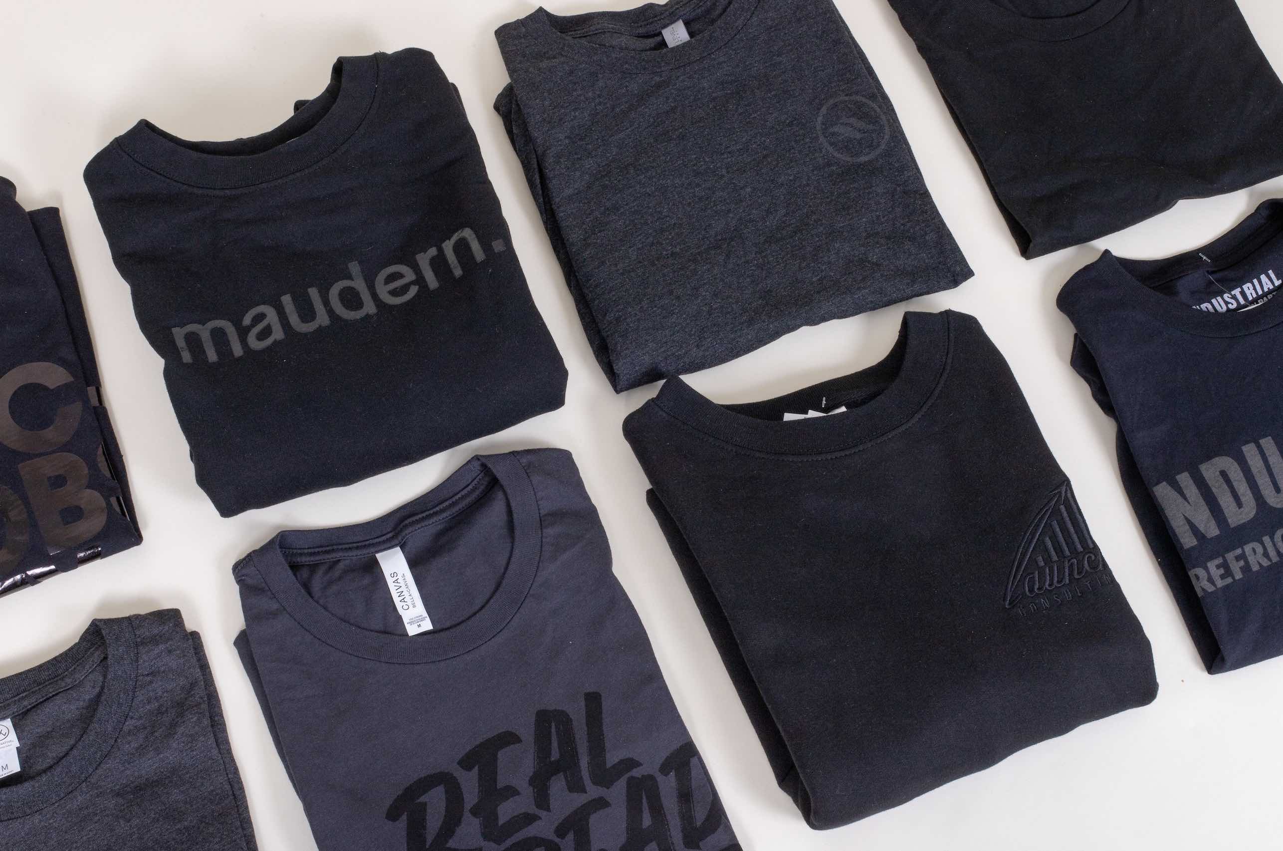 two rows of folded black t-shirts with black imprint
