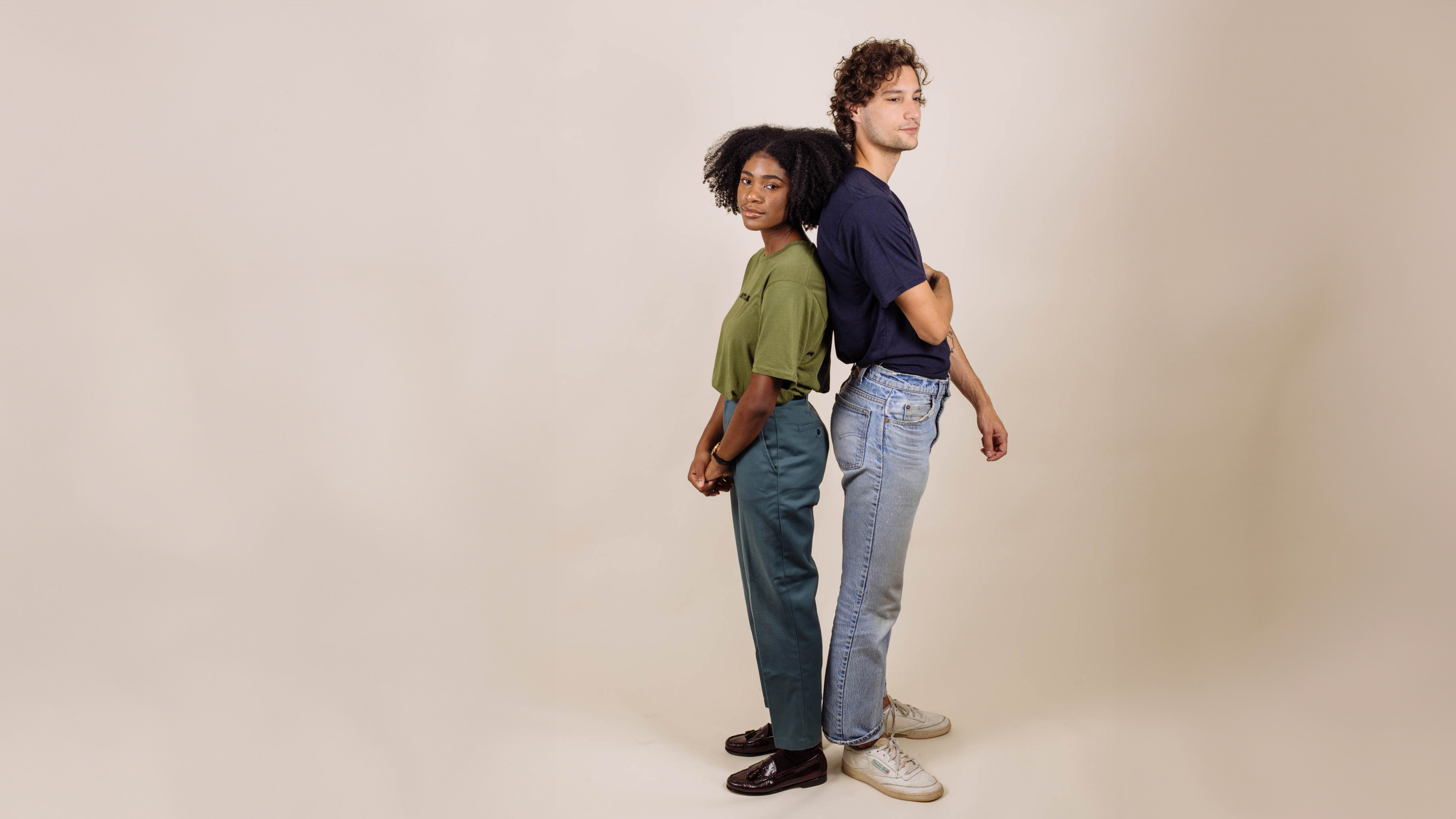 man and a female standing back-to-back in front of a white background