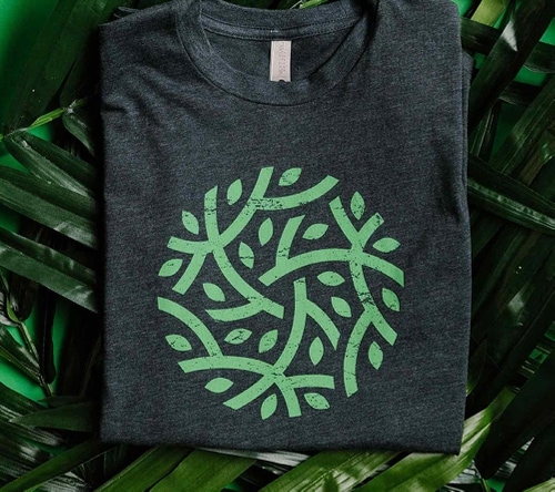 Green branch and leaf design inside of circle printed on a dark green shirt