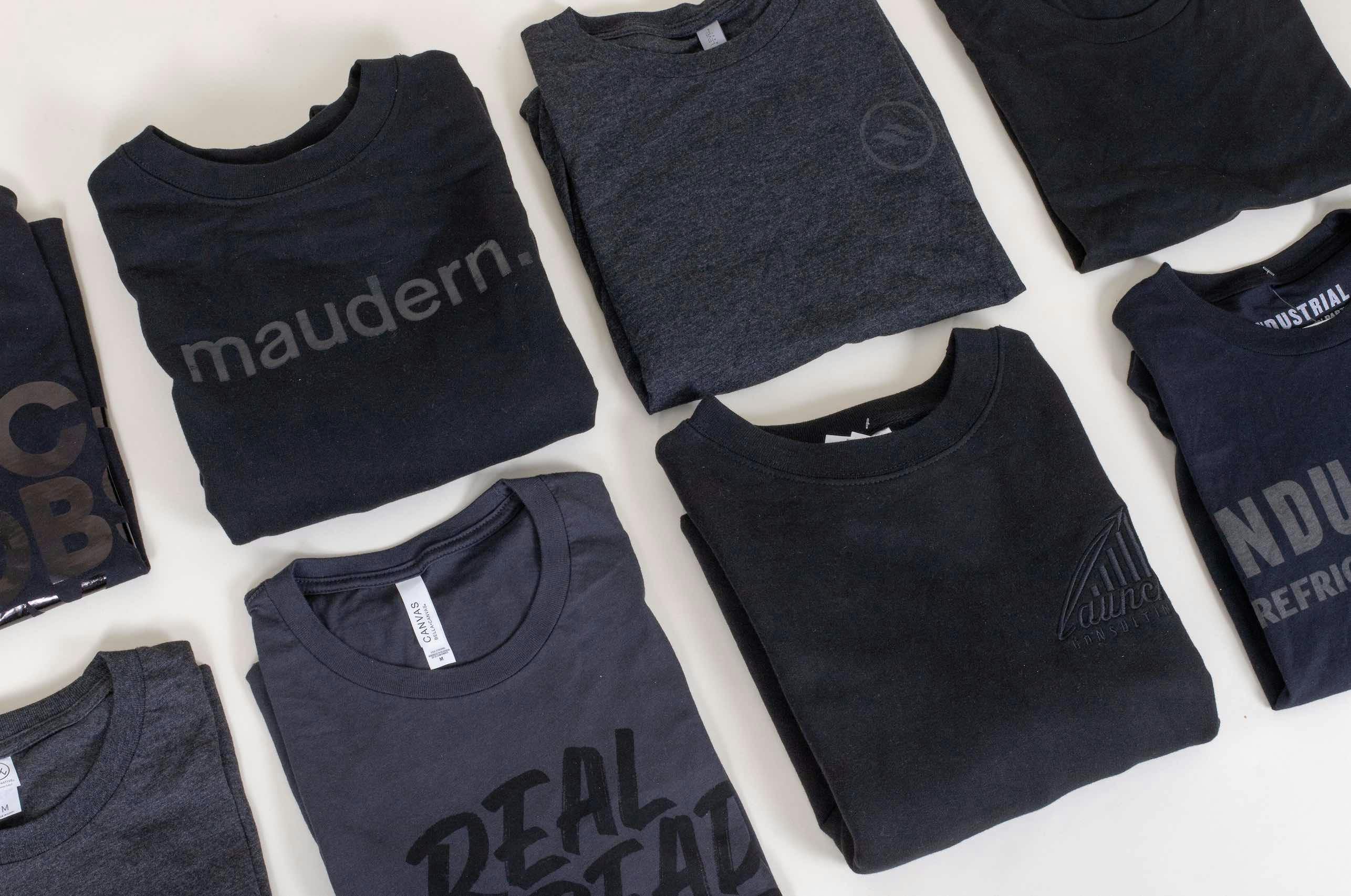 two rows of folded black t-shirts with black imprint