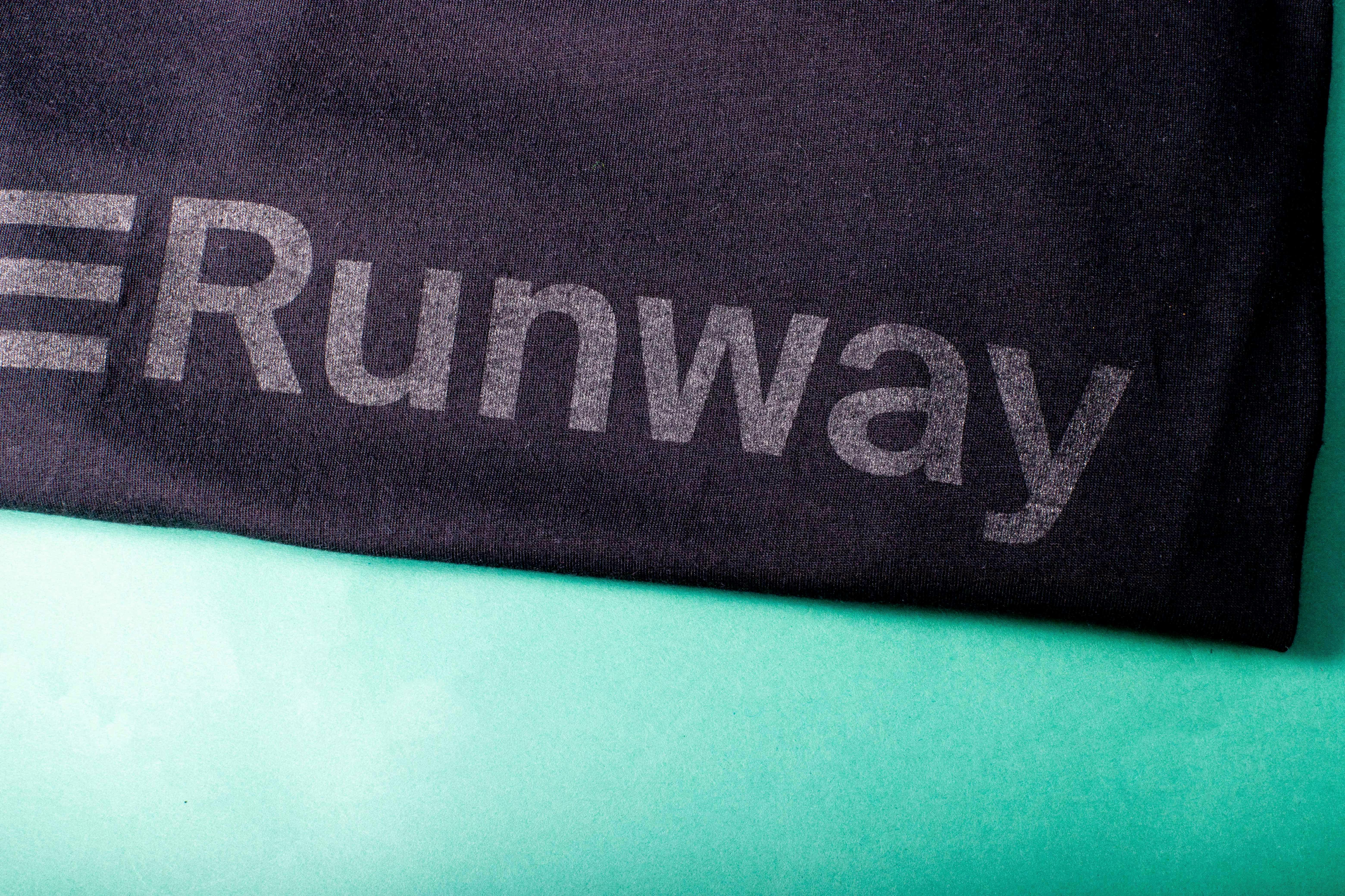 close up view of a black shirt with the word lightly printed Runway logo