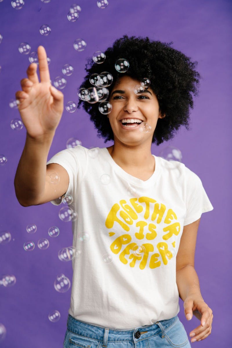 women wearing a white shirt with yellow print in front of a purple background