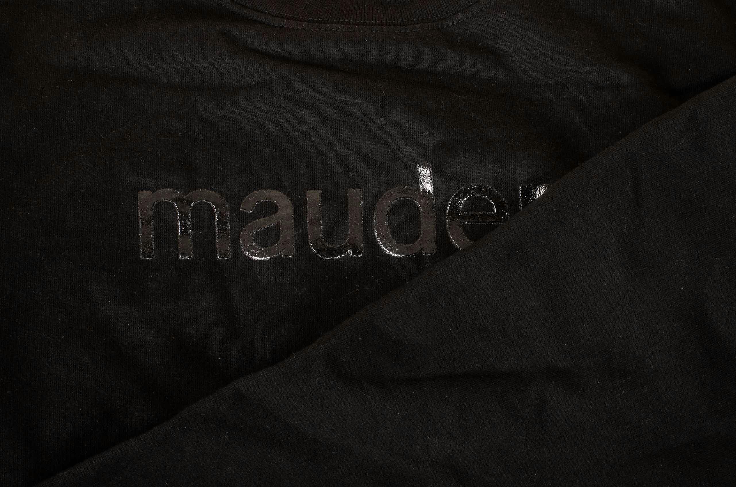 closeup of a black t-shirt with the letters m,a,u.d.e printed on it