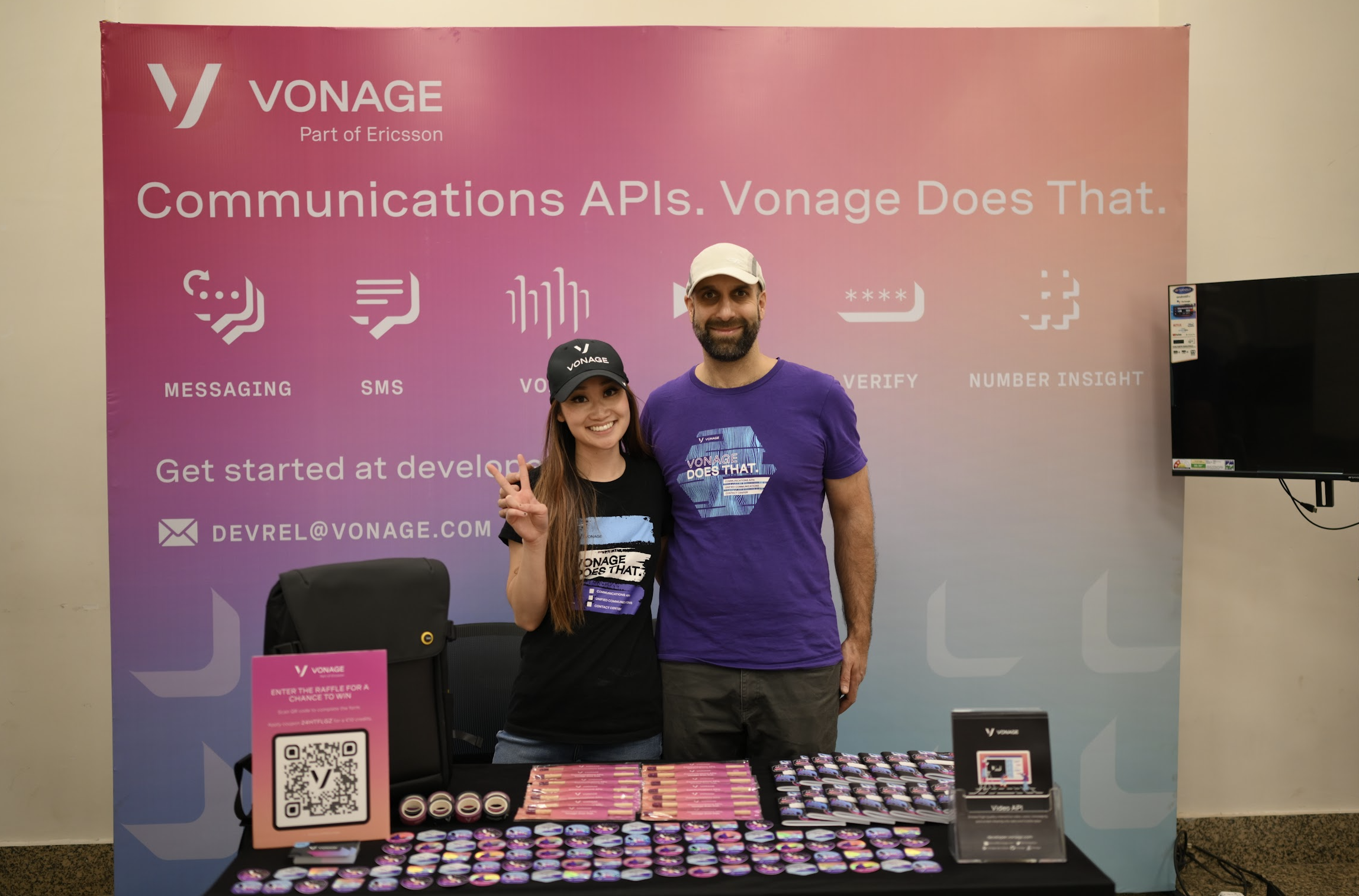 Karl and Diana standing near a table with a sign reading "Communications APIs. Vonage Does That."