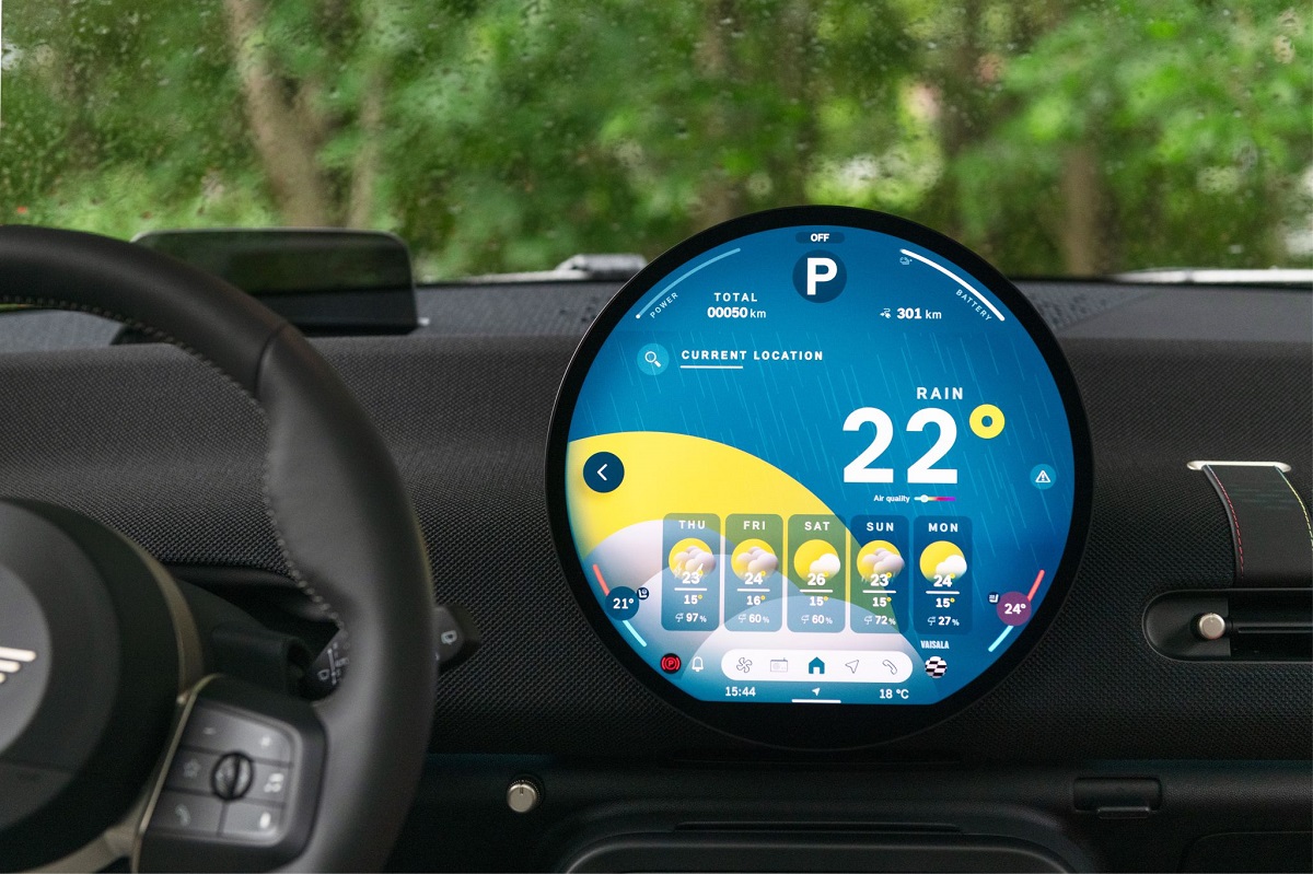 A digital dashboard inside a car displays a screen showing weather information