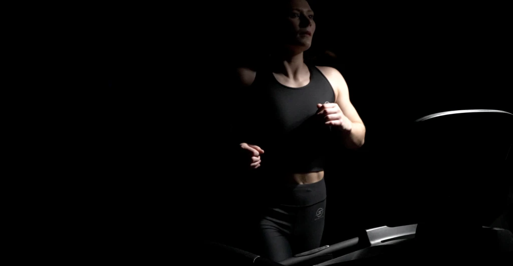 Runner training on a treadmill in low key lighting