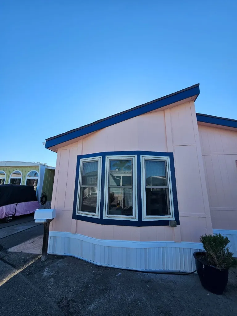 Mobile home bay window with fresh pink paint and navy blue trim — completed project