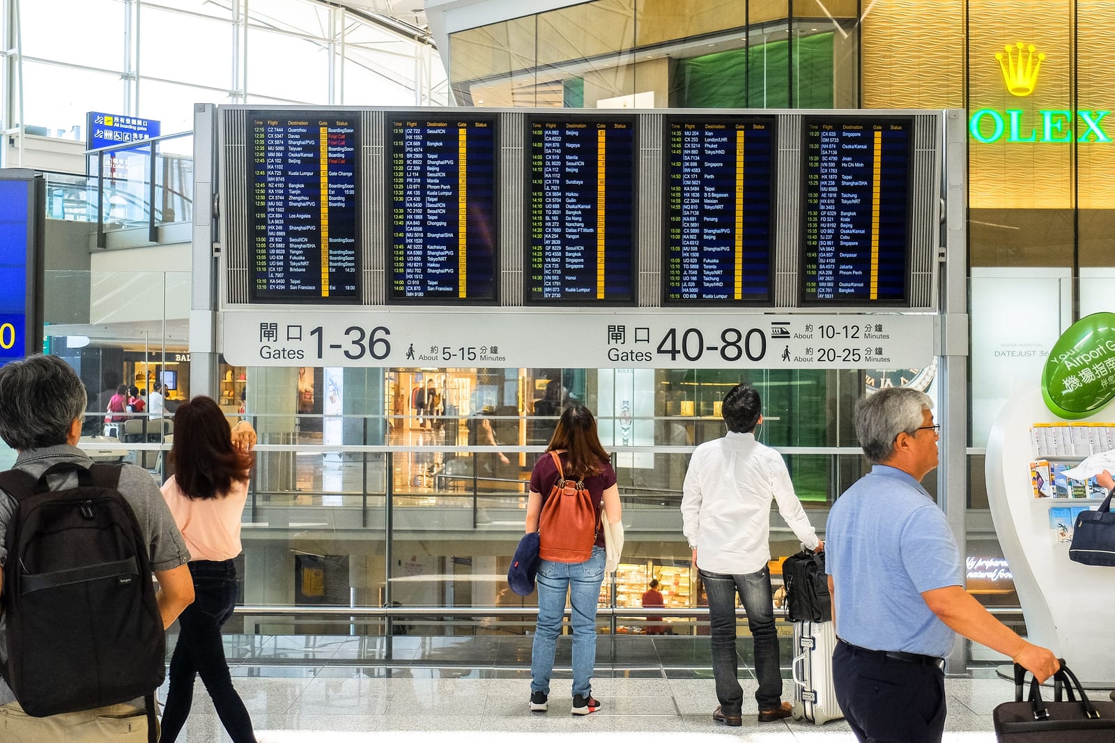 Passengers checking a digital departure board in a busy airport terminal Passengers checking a digital departure board in a busy airport terminal