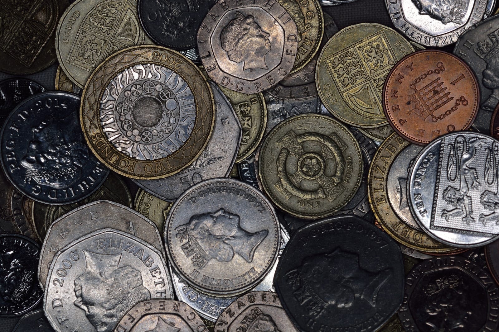 A close-up pile of assorted British coins, including pound, fifty pence and penny pieces