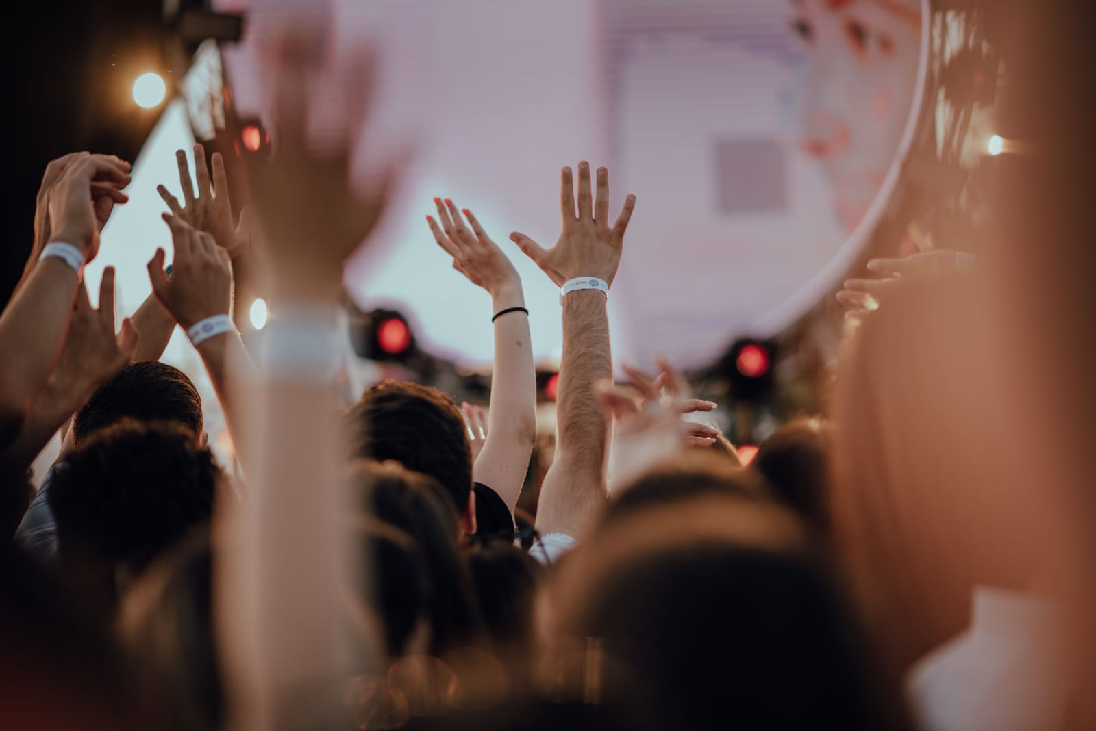 Concert-goers with entry wristbands raising their hands during a live show Concert-goers with entry wristbands raising their hands during a live show