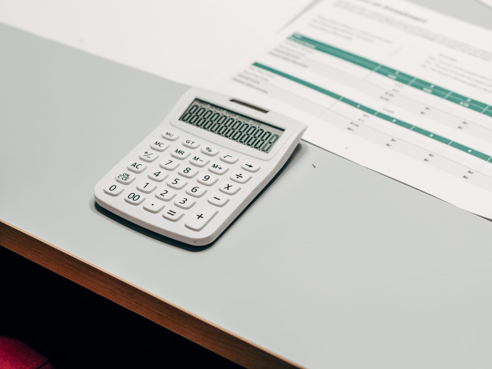 A calculator resting beside a printed financial table on a desk