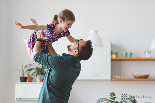 father holding daughter up laughing
