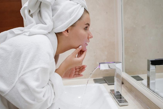 woman looking at clean face in mirror