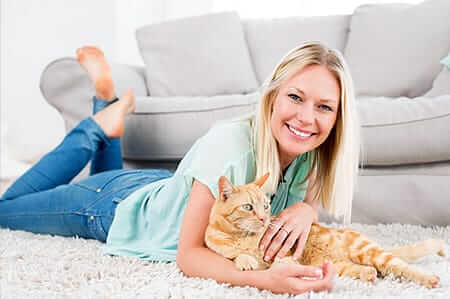 Girl playing with cat on rug