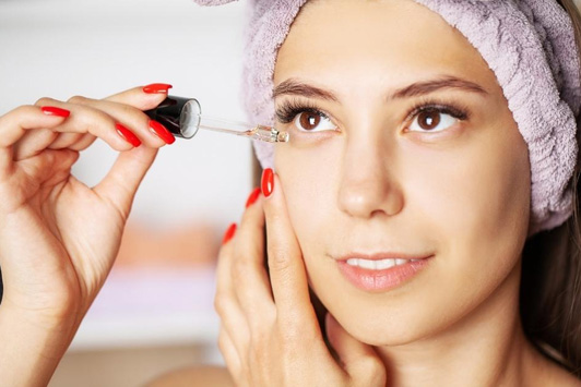 woman putting serum on skin