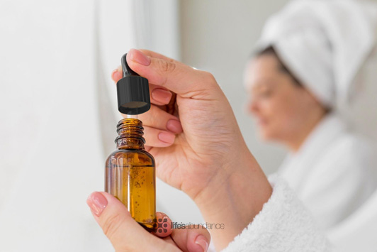 woman using drops of facial serum