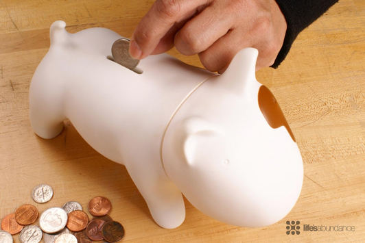 person putting coins in doggy bank