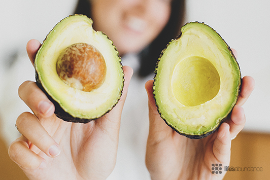 woman holding an avocado cut in half