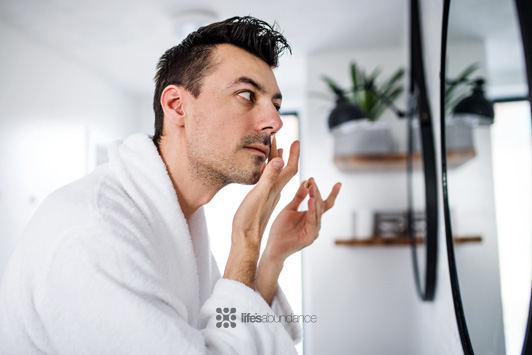man doing skin care routine in mirror