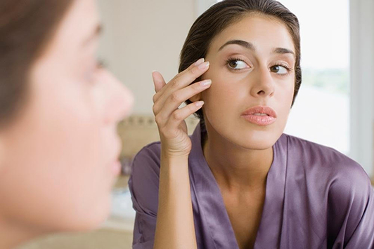 woman looking at face in mirror