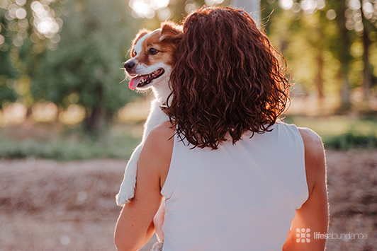 woman holding up her dog outside