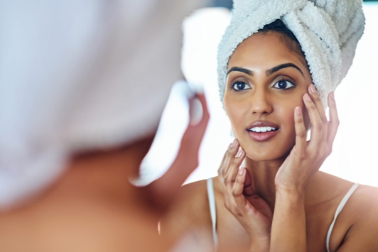 woman looking at clean face in mirror