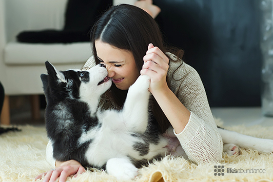woman playing with her dog on the floor