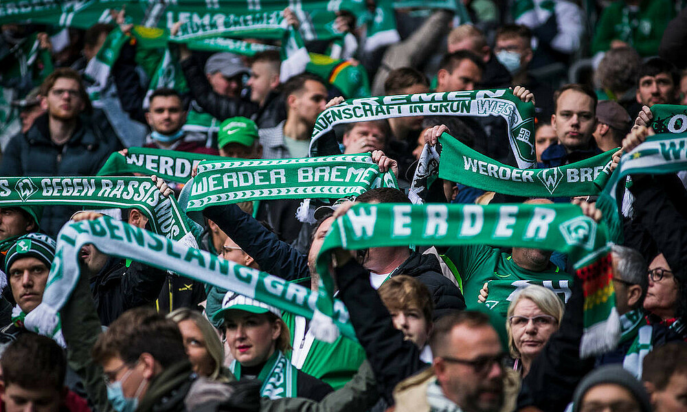 Fans im Weserstadion halten ihre Schals hoch.